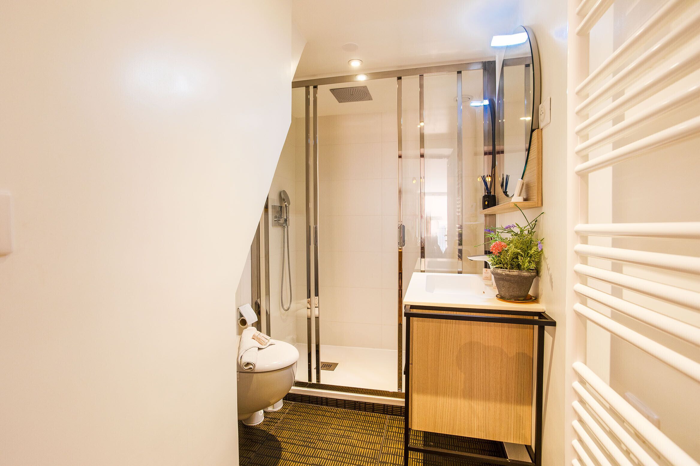 Un baño moderno con cabina de ducha de vidrio, inodoro y lavamanos con mueble de madera.