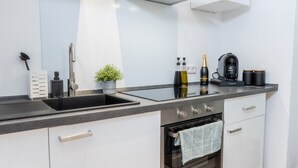 Una cucina moderna con un piano di lavoro nero, elettrodomestici in acciaio inossidabile, un lavello e una piccola pianta in vaso.