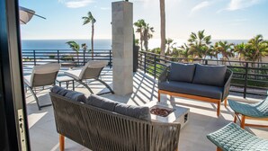 Un balcon avec des sièges d’extérieur, un pilier en béton et une vue sur l’océan.