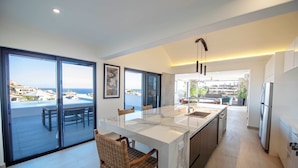Une cuisine moderne dotée d’un grand îlot central, d’un coin repas offrant une vue agréable et d’un balcon spacieux.