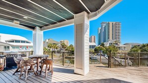 Um deck de madeira com churrasqueira e mesa, com vista para um porto de iates e prédios altos.