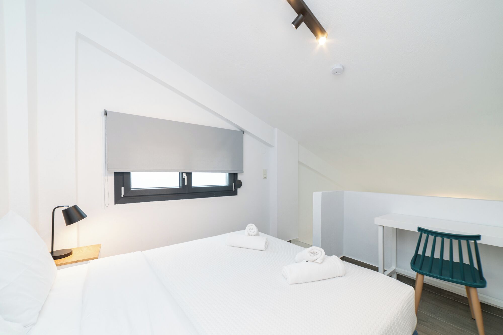 Une chambre d’hôtel moderne, dotée d’un grand lit, d’un bureau et d’une chaise.