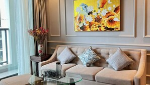 A modern living room with a beige sofa, a glass coffee table, and a ceiling fan. - Luxury 2BR Apartment with Ocean view (Đà Nẵng)