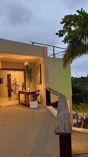 A modern house with a patio area, a dining table, and potted plants. - Pousada Recanto dos Pássaros (Porto Seguro)