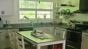 Una cocina con una mesa de comedor, sillas, una estantería para vinos y una estufa.