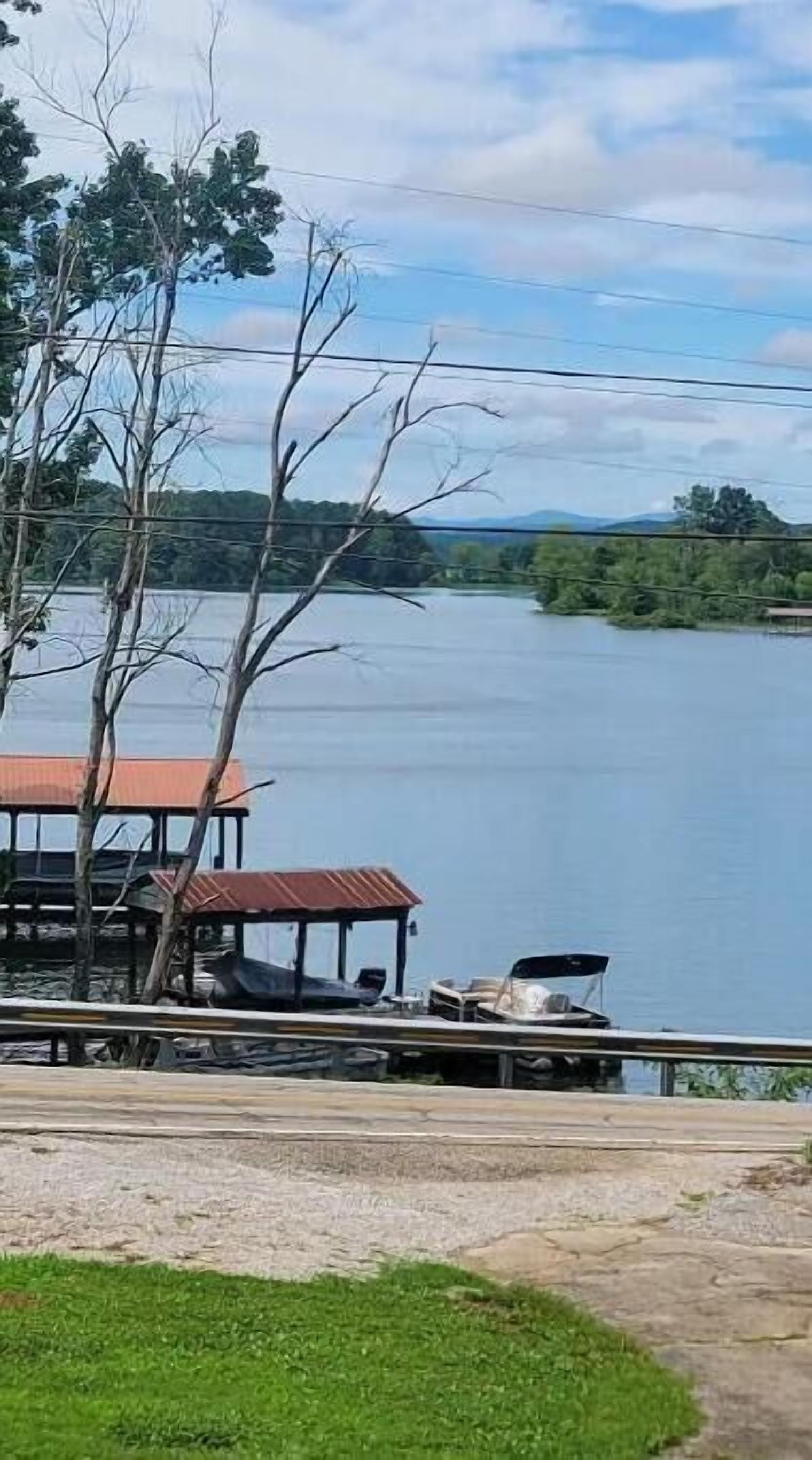 A lakeside view with a dock and a small building with a red roof.