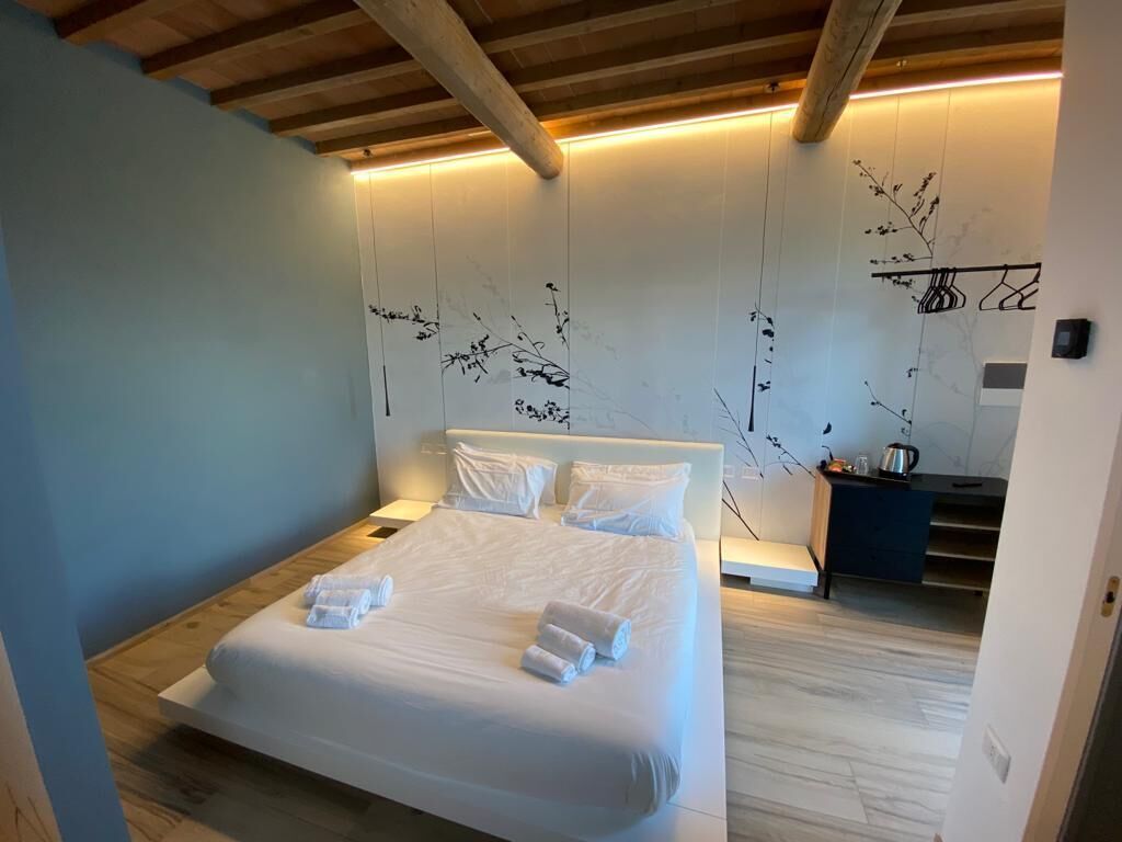A modern bedroom with a large bed, white linens, and a minimalist design.