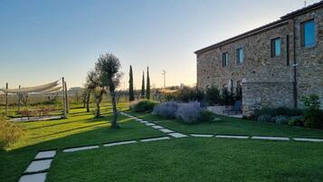 A stone building with a paved garden path, outdoor seating, and a clear sky.