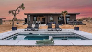 A modern house with a pool, lounge chairs, and desert landscaping.