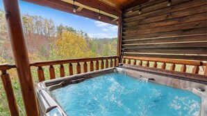 Un jacuzzi en una terraza de madera con vistas a árboles otoñales.