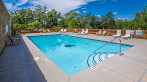Una piscina rectangular con indicador de profundidad de 3 pies, rodeada de sillones de descanso y una valla de madera.