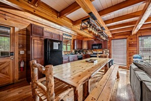 A rustic cabin-style kitchen with wooden beams, a central island, and built-in appliances.