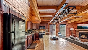 Una cocina amplia con suelos de madera, una gran mesa de comedor, horno empotrado y chimenea.