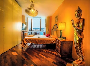 Relax in this serene space with a large bed, city view, and elegant chandelier.