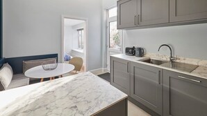 A compact kitchen with grey cabinets, a marble countertop, and a sink.