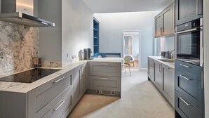A modern kitchen with grey cabinetry, a marble countertop, and built-in appliances.