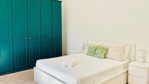 A bedroom with a bed, white nightstands, a green wardrobe, and a white ceiling. - VILLA NOLELU - vacation home with large panoramic terrace (Barano D'ischia)