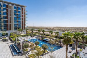 Un hotel con piscina en la azotea, palmeras y vistas al desierto.