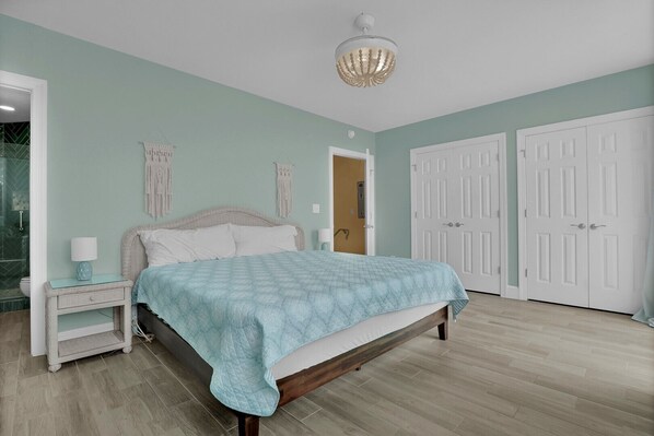 Une chambre à coucher avec un lit, des tables de chevet, un lustre et des portes blanches.