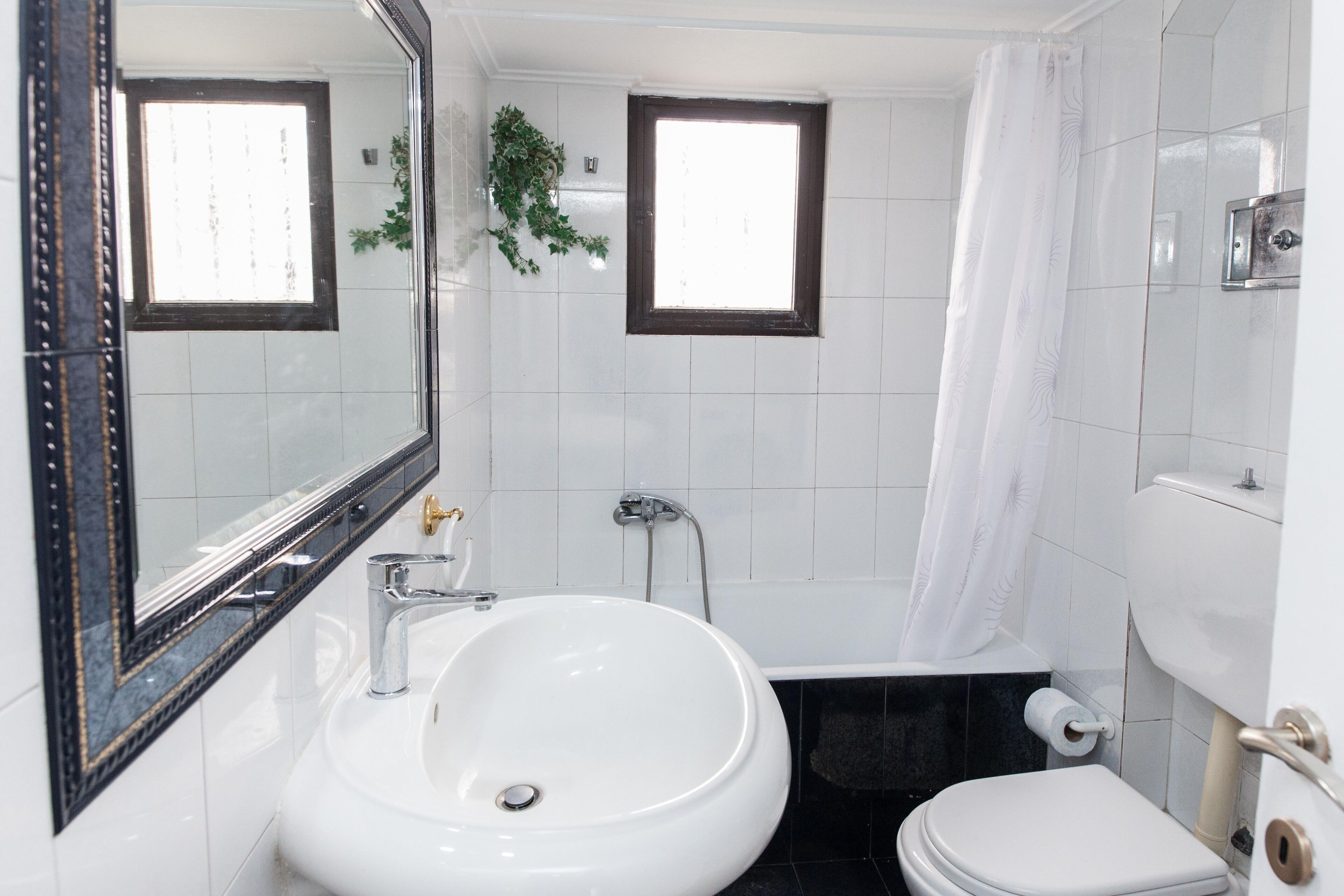 A bathroom with a white sink, a mirror, a toilet, and a shower curtain.