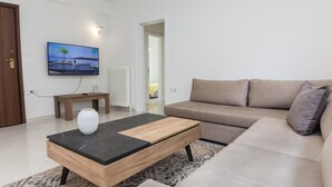 Ein modernes Wohnzimmer mit einem beigefarbenen Sofa, einem Holztisch und einem flachbildfernseher, der an der Wand befestigt ist.