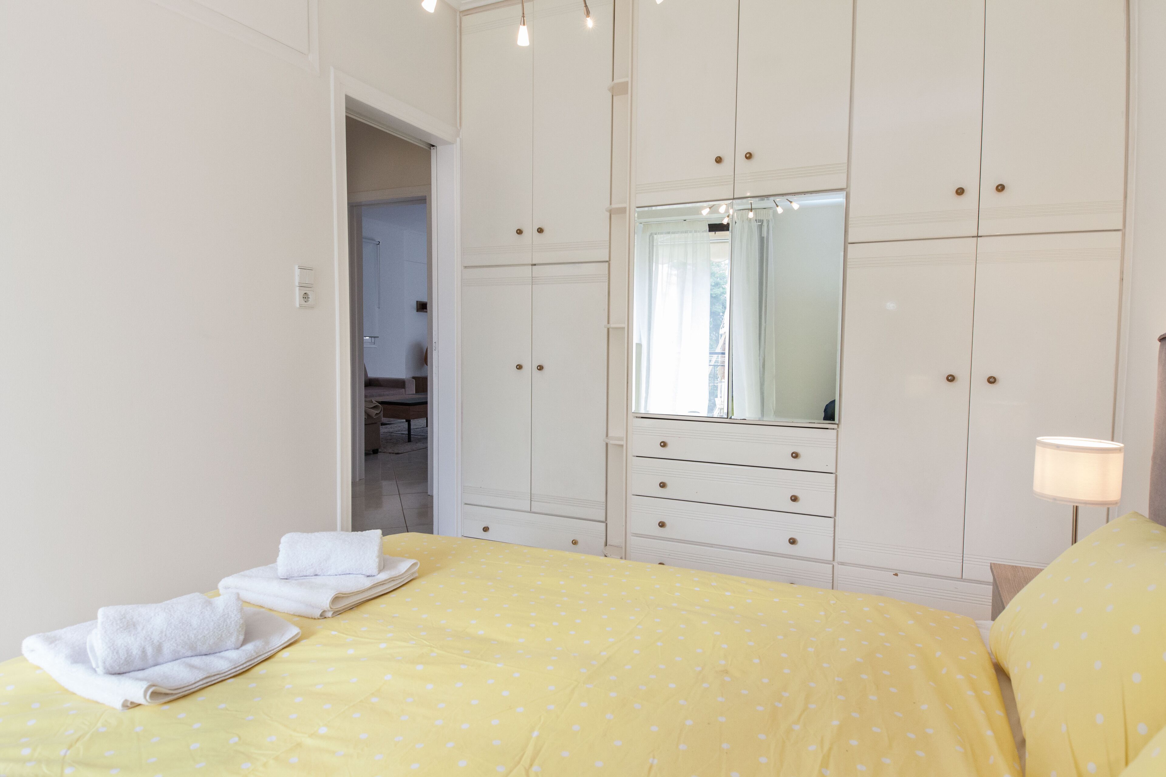 Une chambre à coucher comprenant un lit, une armoire, un miroir et une table de chevet avec une lampe.