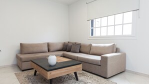 Ein modernes Wohnzimmer mit einem beigefarbenen Modulsofa, einem Holztisch und einem gemusterten Teppich.