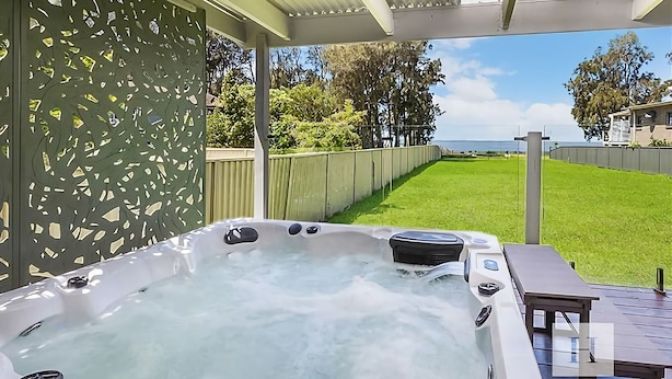 A hot tub with a wooden deck and a view of a grassy yard and trees. - The Sweet Retreat - Hot tub with Lakeviews! (Tuggerawong)