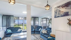 A modern living room with a sofa, armchairs, a coffee table, and a painting on the wall. - The Sweet Retreat - Hot tub with Lakeviews! (Tuggerawong)