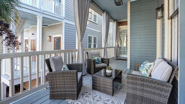 A covered porch with wicker furniture, a patterned rug, and a view of neighboring buildings. - The Alfred Inn, Victorian District | Modern Flare (Savannah)
