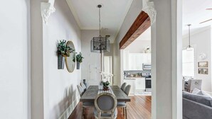A dining area with a wooden table, chairs, and a hanging light fixture. - The Alfred Inn, Victorian District | Modern Flare (Savannah)