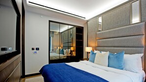 Une chambre d’hôtel moderne avec un grand lit, un miroir et une table de chevet avec une lampe.