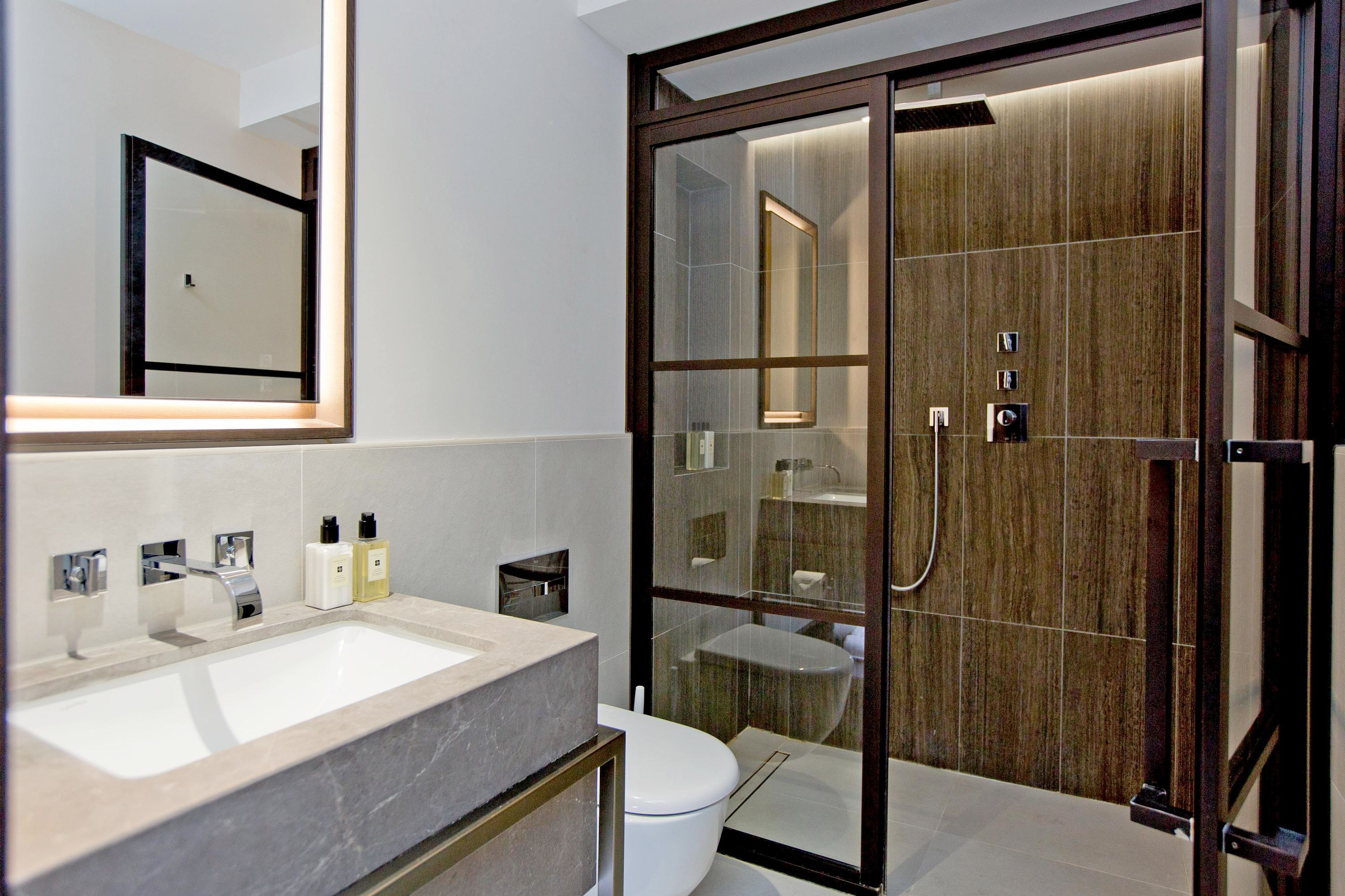 A modern bathroom with a large sink, toilet, and glass-enclosed shower area.