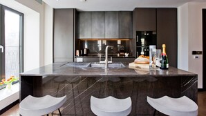 A modern kitchen with a central island, bar stools, and a large window. - 3-bed Deluxe Apt 413 (London)
