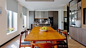 Una cocina moderna con una mesa de comedor de madera, un bol de fruta y vistas al área de comedor.