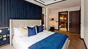 Una habitación de hotel moderna con una cama grande, una mesita de noche, un armario y un baño visible a través de una puerta abierta.
