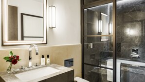 Un baño moderno con un espejo grande, un lavamanos, un inodoro y zona de ducha con mampara de cristal.