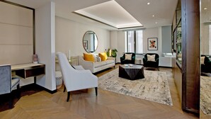 Una sala de estar moderna con un sofá, sillones, una mesa de centro, un escritorio y un espejo grande.