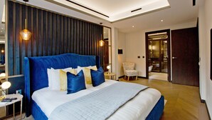 Habitación de hotel moderna con una cama grande, zona de estar y vistas al pasillo.