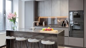 Una cocina moderna con una isla de mármol, electrodomésticos de acero inoxidable y un ventanal grande.