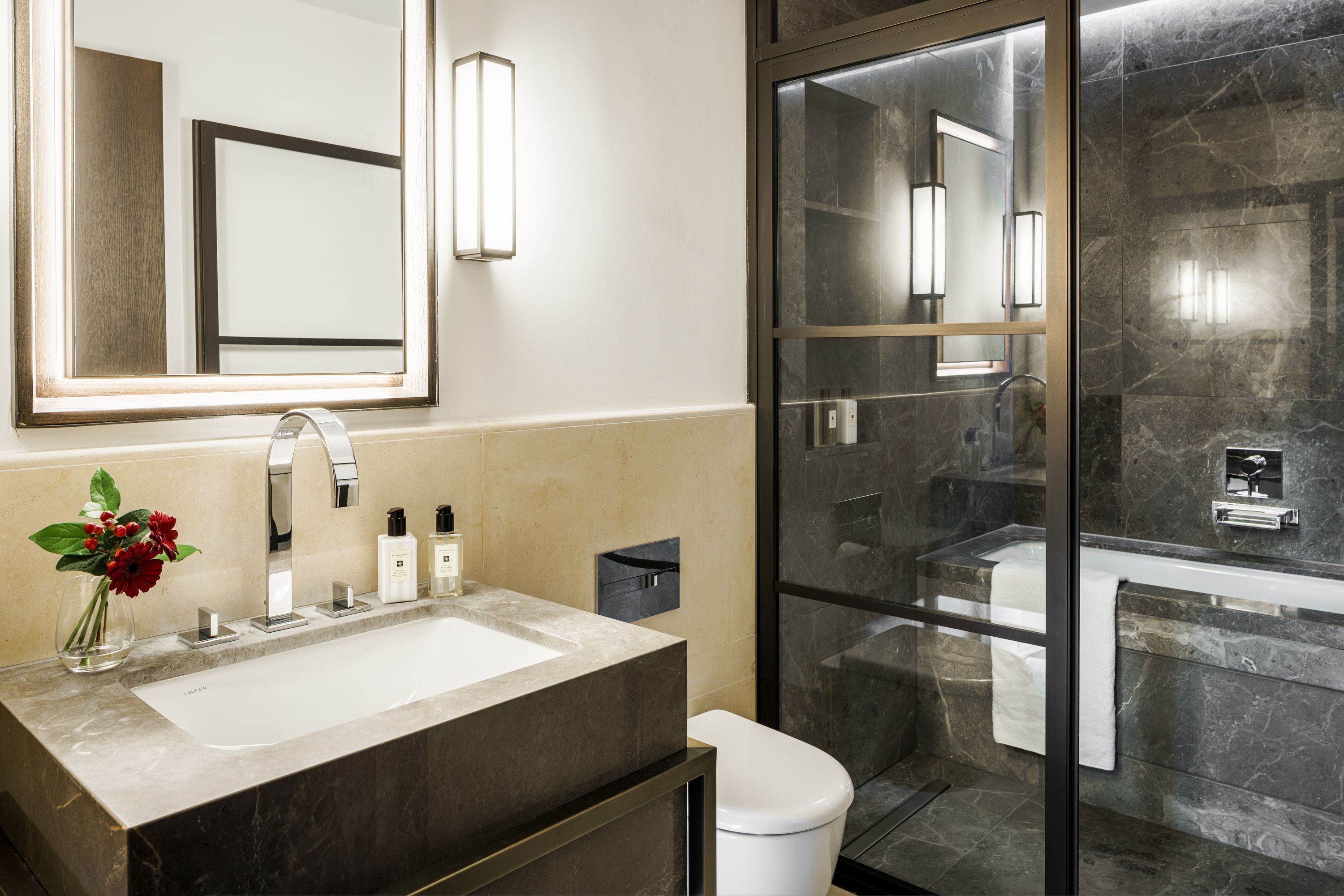 A modern bathroom with a large mirror, a sink, and a glass-enclosed shower.