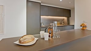 Una cucina moderna con un piano di lavoro in marmo, una pagnotta di pane, una macchina da caffè e una vetrina con dolci.