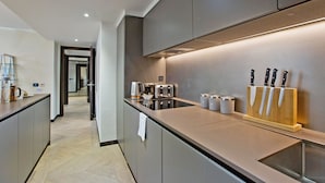 Una cucina moderna con mobili grigi, un piano di lavoro in acciaio inox, un tostapane integrato e un portachiodi.