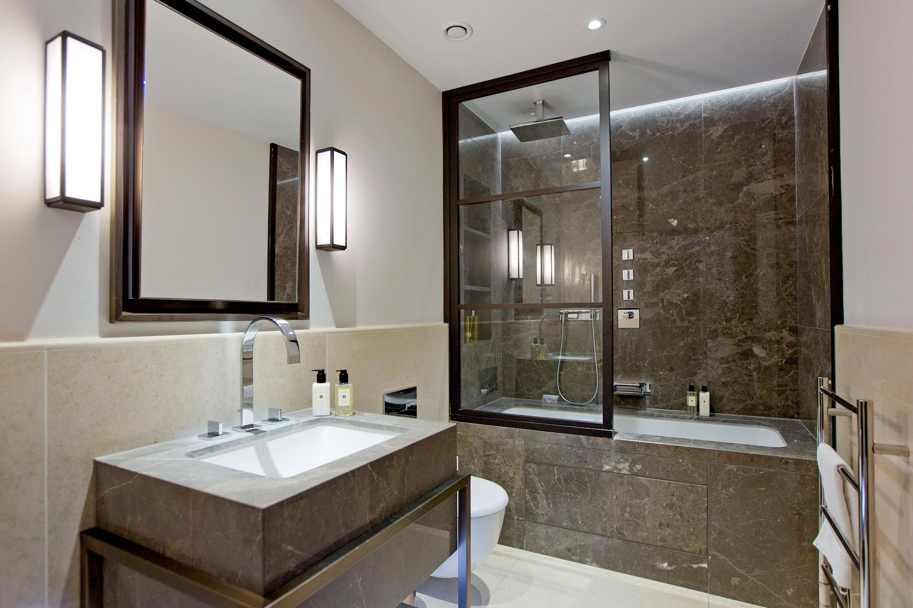 Une salle de bain moderne avec un grand miroir, un lavabo, des toilettes et un espace douche.