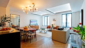 Un salon moderne comprenant un coin repas, un canapé, un téléviseur et une grande fenêtre.