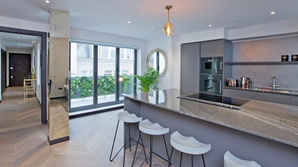 Una cocina moderna con una isla grande, taburetes de bar y vistas al exterior.