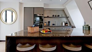 Una cocina moderna con encimera de mármol, un espejo redondo y una zona de estar con taburetes.