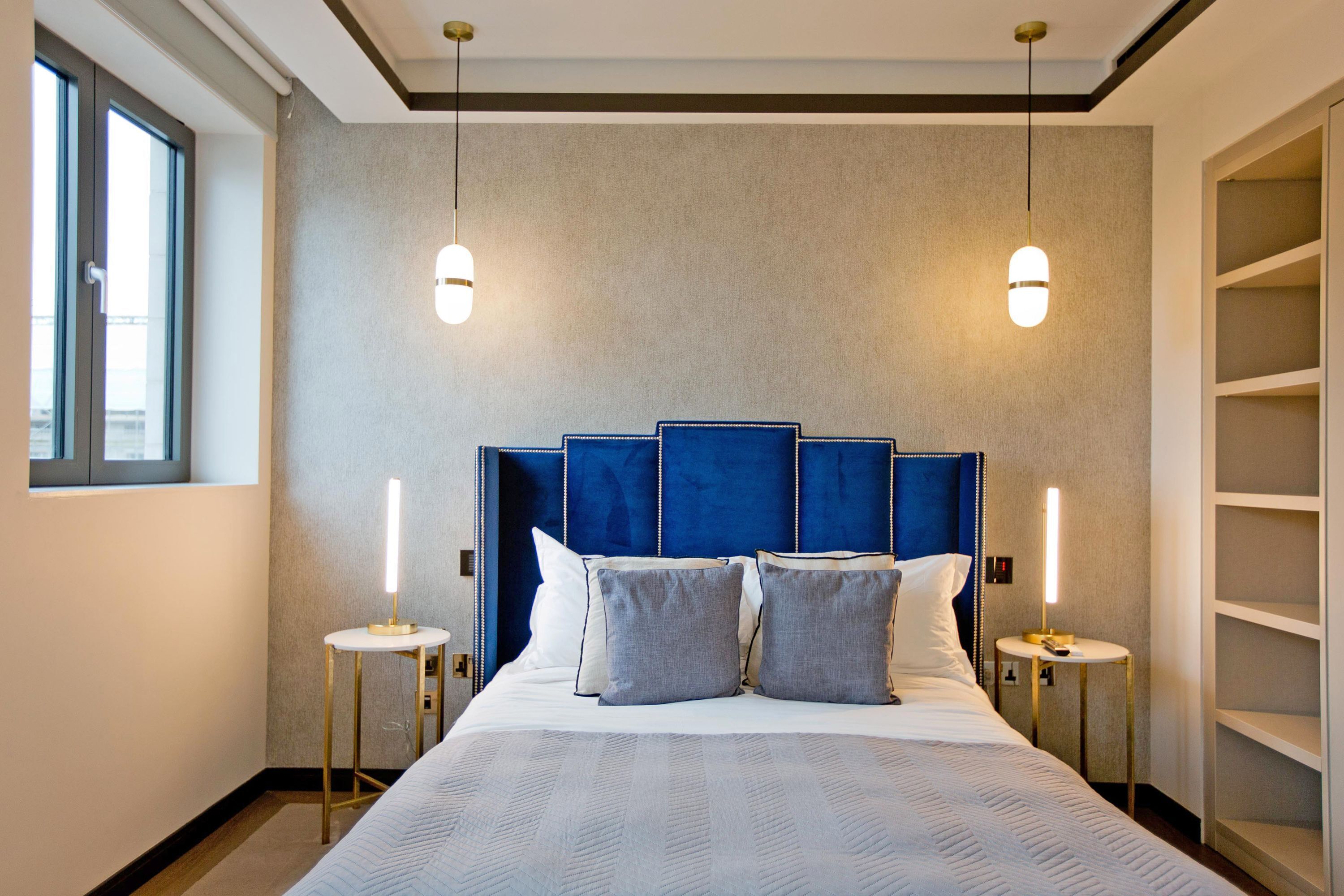 Une chambre d’hôtel moderne avec un grand lit, deux tables de chevet et une armoire intégrée.