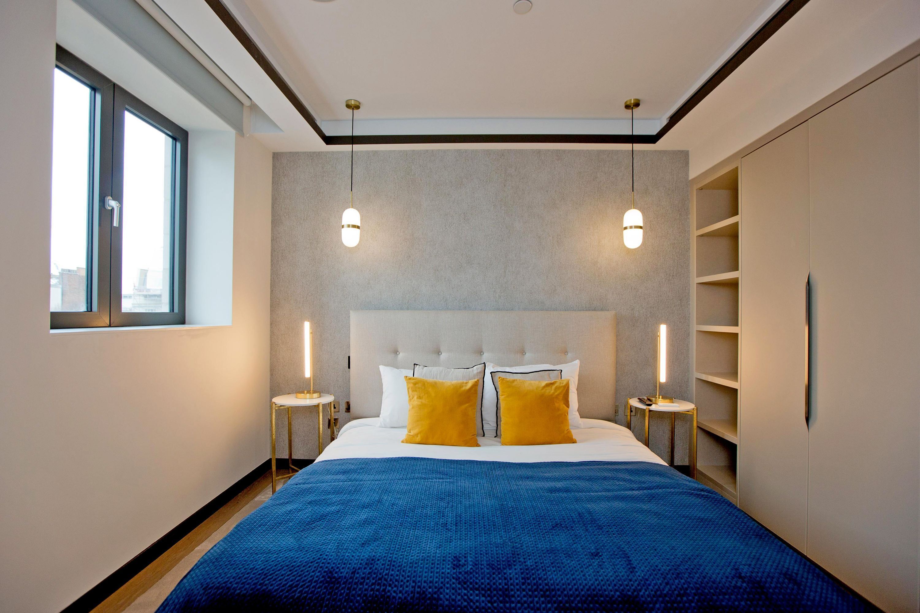 Ein Hotelzimmer mit einem großen Bett, zwei Nachttischen, einem Kleiderschrank und einem Fenster.
