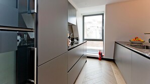 A modern kitchen with stainless steel appliances, a large window, and a fruit bowl on the counter. - 2-bed Superior Apt 416 (London)
